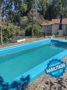 a blue swimming pool with a hacienda sign on it at Altos de la Laguna in Chascomús