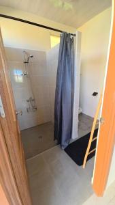 a bathroom with a shower with a blue shower curtain at AK Lodge Raiatea in Raiatea