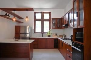 a kitchen with wooden cabinets and stainless steel appliances at Ashasha Villa in Negombo