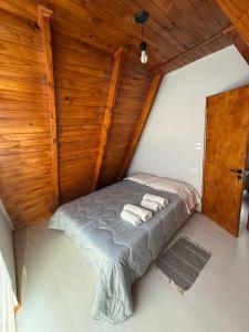 a bed in a room with a wooden wall at Cabañas Alpinas M&M in Perito Moreno