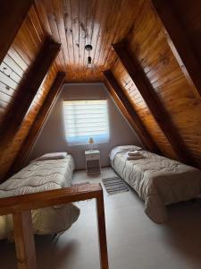 a attic bedroom with two beds and a window at Cabañas Alpinas M&M in Perito Moreno +24 photos