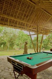 a pool table under a pavilion with a lion in the background at Ardan Maison The Garden Villas in Ubud