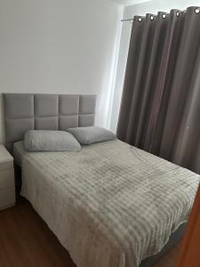 een slaapkamer met een bed met een grijs gordijn bij Aconchego Moro- Apto708, T-2 in Barra Velha