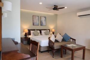 a bedroom with a bed and a table and a couch at Frangipani Langkawi Resort in Pantai Cenang