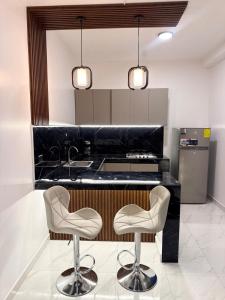 eine Küche mit zwei weißen Stühlen und einer schwarzen Theke in der Unterkunft Luxury suite in Puyo in Puyo