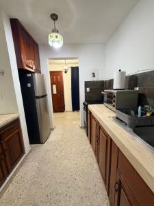 een keuken met houten kasten en een zwarte koelkast bij Comfortable ground floor apartment with 2 bedrooms in Villahermosa