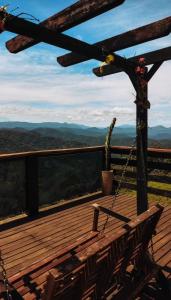 a swing on a deck with a view of the mountains at Chalés Refúgio nas montanhas in Guaratuba