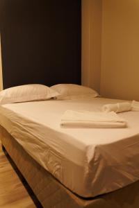 un letto bianco con due asciugamani bianchi di Lou Suites - 15 - Cantinho Charmoso a Guarapuava