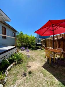 a patio with a table and a red umbrella at TINY HOUSE Refugio de Mar in Mar del Plata