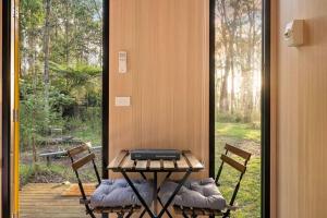 a table and two chairs on a porch with a window at Quantum Field by Tiny Away in Toolangi