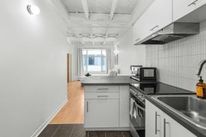 a white kitchen with a sink and a microwave at Métropolitain Le Cachet in Quebec City +15 photos