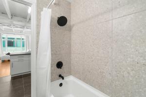 a bathroom with a shower with a white tub at Métropolitain Le Cachet in Quebec City