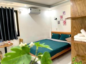 ein Schlafzimmer mit einem Bett mit blauen Laken und einer Pflanze in der Unterkunft Win House Huế in Thôn Dương Phẩm