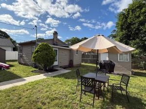 een tafel en stoelen met een parasol in de tuin bij Oakland Beach Cottage - Sleeps up to 4 in Warwick