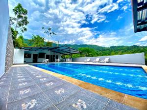 a swimming pool with chairs next to a building at Finca Tres Potrillos Villeta in Villeta
