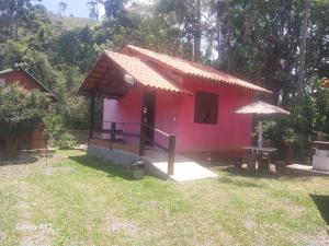 une petite maison rose avec une table devant elle dans l'établissement Chalé 1, à Resende