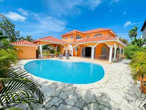 a house with a swimming pool in front of it at Villa Tropical Cabarete in Sosua