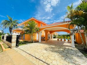 an orange house with palm trees in front of it at Villa Tropical Cabarete in Sosua