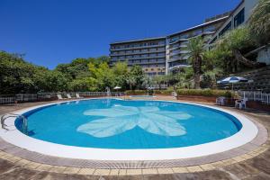 een groot zwembad met een groot gebouw op de achtergrond bij Higaki Hotel in Gamagori