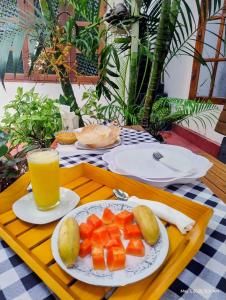 een tafel met een fruitschaal en een glas sinaasappelsap bij DKC Apartment in Ahangama
