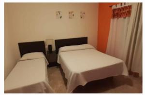 two beds in a room with white sheets at El Tito Alojamiento in San Roque