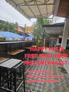 een bord met de tekst: happy hour, gratis shot bier, gratis ontbijt bij LPQ Hostel in Luang Prabang