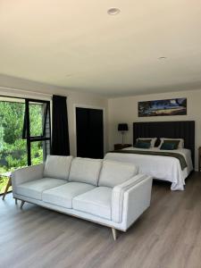a living room with a couch and a bed at Kauri Cabins Tranquil Retreat in Whitianga