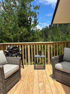 a patio with two chairs and a grill on a deck at Kauri Cabins Tranquil Retreat in Whitianga