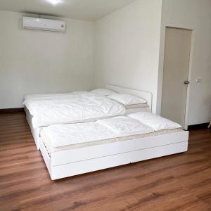 two beds in a room with white walls and wooden floors at Prachanngam Homestay in Ban Sam Laem
