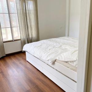 a white bed in a white bedroom with a window at Prachanngam Homestay in Ban Sam Laem