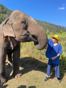 een man met een hoed staat naast een olifant bij DoiLom Farmstay in Ban Muang Kut