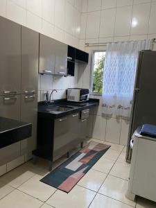 a small kitchen with a sink and a refrigerator at Casa completa com dois quartos e estacionamento grátis in Serra