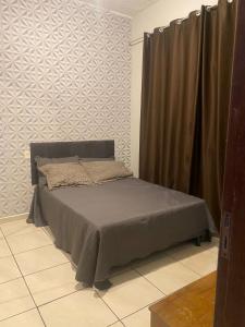 a bed in a room with a wall at Casa completa com dois quartos e estacionamento grátis in Serra