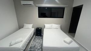 two beds in a small room with a window at Departamento Liss in Mérida