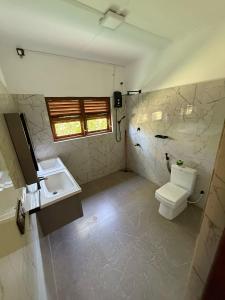 a bathroom with a toilet and a sink and a window at 108 Palms Beach Resort in Trincomalee