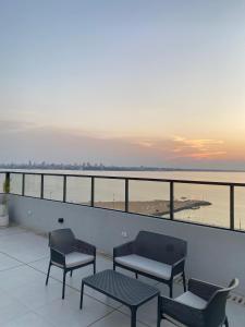 a balcony with chairs and tables and a view of the ocean at Lujoso Apartamento en edificio frente a la playa San José! in Encarnación