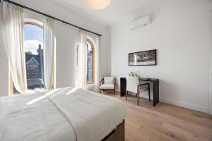 a bedroom with a bed and a desk and windows at The Brick Hotel - The Loft in Toronto