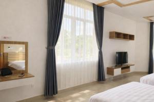 een slaapkamer met een raam, een spiegel en een televisie bij Hà Linh Hotel Vũng Tàu in Bà Rịa