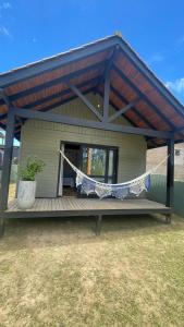 a house with a porch with a hammock on it at Novidade-Cabana Praia do Rosa in Imbituba