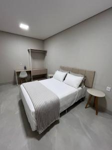 a bedroom with a large white bed and two tables at Atalaia Apart in Sinop