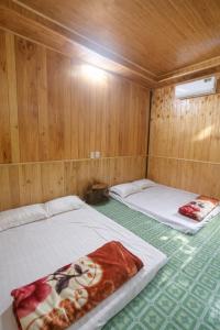 two beds in a room with wooden walls at Thu May Homestay A Lưới in A Lưới (1)