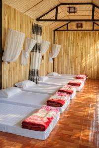 a row of beds in a room with wooden walls at Thu May Homestay A Lưới in A Lưới (1)