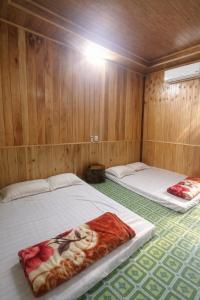 two beds in a room with wooden walls at Thu May Homestay A Lưới in A Lưới (1) +22 photos