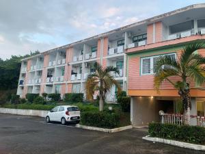 a white car parked in front of a building at Studio Cosy Anse Mitan Trois Ilets in Les Trois-Îlets