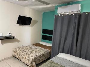 a small bedroom with two beds and a tv at Hotel en Acapulco Bora Bora in Acapulco