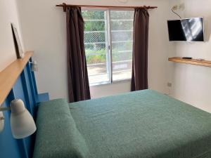une chambre avec un lit vert et une fenêtre dans l'établissement Dunas Delfin, à Monte Hermoso