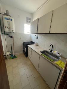 a small kitchen with a sink and a stove at Polimar in Mar de Ajó