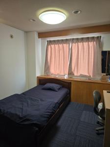 een slaapkamer met een bed, een raam en een bureau bij business hotel furusatoビジネスホテルふるさと in Ureshino