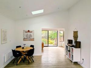 a white living room with a table and chairs at Mollymook Den Coastal Retreat - Walk to Beach & Town in Mollymook