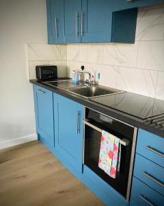 a kitchen with blue cabinets and a sink at Quiet Riverside Stopover by the Shannon in Leitrim